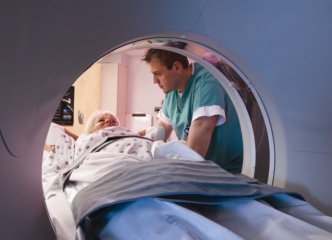 Photo of patient and healthcare professional with MRI machine. Couresy of NIH Dept. Heath and Human Services.